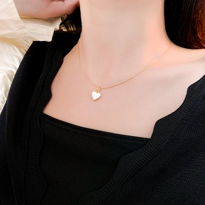 Détail du collier coeur doré avec incrustation de nacre blanche porté au cou