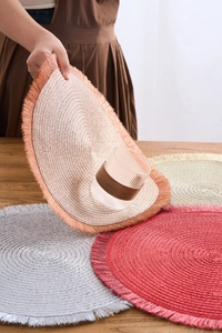 Detail of round woven placemat with metallic tassels showing texture and flexibility