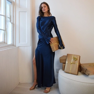 Detailed view of dark blue satin dress with long sleeves and high slit on model