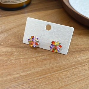 Close-up of colorful flower stud earrings with faceted beads on a display card