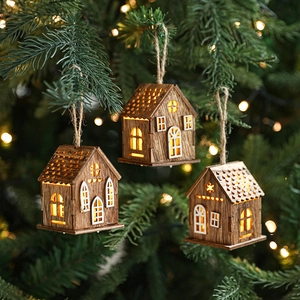 Tre casette di Natale in legno con LED appese ai rami di un albero di pino