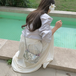 Detail of silver sequin handbag with chain strap shown by a swimming pool