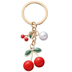 Close-up of red enamel cherry keychain with gold metal hardware and white faux pearl detail