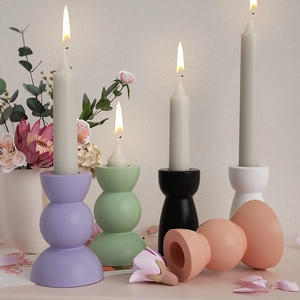 Close-up of minimalist geometric ceramic candle holders in matte pastel colors and black