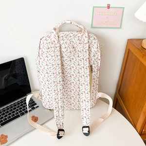 Floral canvas backpack in cream white with pink flower patterns on a minimal workspace