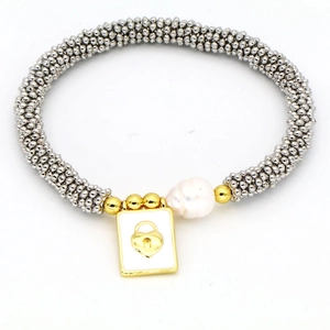 Detail of beaded bracelet with irregular white pearl and golden heart lock pendant