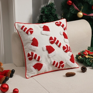 Weihnachtliches Kissen mit Stickereien von Weihnachtsmütze und Zuckerstange auf Sofa