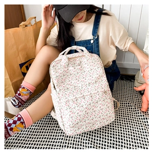 Detailed view of white floral backpack with pink petals and front zipper pocket