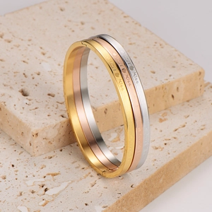 Three-piece stainless steel bangle set in gold, rose gold, and silver with Love Kiss engraving
