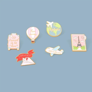Detailed flat lay of travel-themed alloy enamel pins featuring airplanes and hot air balloons