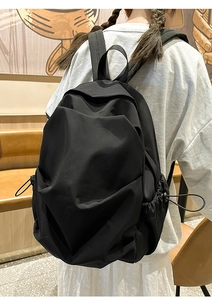 Detailed view of black waterproof nylon backpack featuring drawstring side pockets
