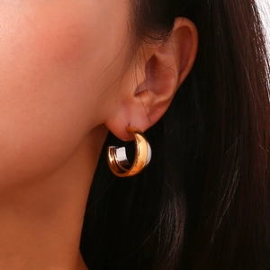Close-up of two-tone 18K gold-plated C-shaped earrings worn by a model in detail view