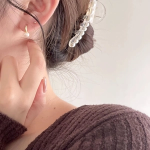 Close-up of a delicate gold pearl drop earring worn by a model in a soft elegant style