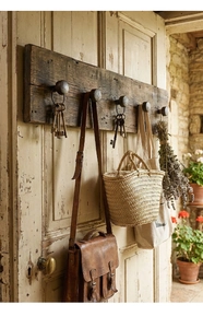 Detail of vintage cast iron hooks on a rustic wood board showing storage of bags and dried flowers