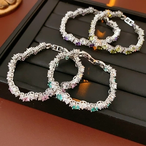 Detail of silver tennis bracelets featuring colorful cubic zirconia on a black stand