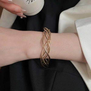 Close-up of golden hollow woven open cuff bracelet on wrist with elegant minimalist style
