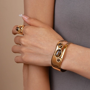 Detail eines 18k vergoldeten Armreifs und Ring-Sets aus Edelstahl mit braunem Tigerauge-Stein