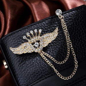 Elegant gold crown wing brooch with rhinestone tassels on black leather background
