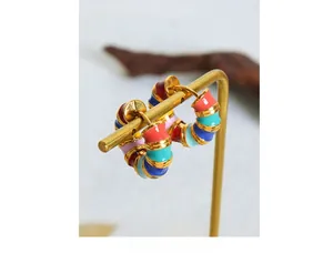 Detail of colorful rainbow enamel C-shaped gold hoop earrings on a minimalist stand