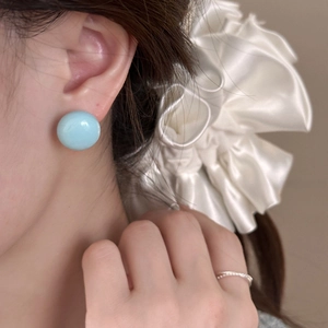 Boucles d'oreilles rondes bleu ciel avec finition en résine brillante portées par un mannequin
