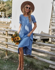 Détail d'une robe midi bleue à volants et col rond sous une lumière naturelle éclatante