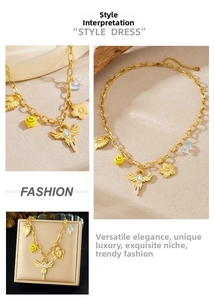 Details einer goldenen Gliederkette mit Flügeln, Blumen und Smiley-Anhängern im Set