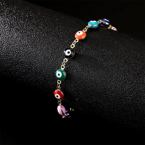Gold-plated Evil Eye bracelet with multi-color enamel charms on a black display stand