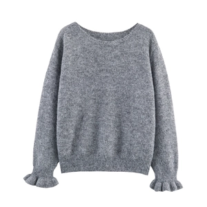 Détail d'un pull gris en maille ajourée avec poignets à volants élégants et doux