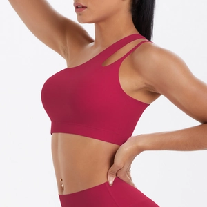 Detail of dark red one-shoulder sports bra with laser-cut straps and matte fabric
