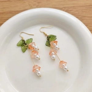 Detailed macro view of handmade pink bellflower earrings with green leaves and white pearls