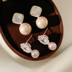 Macro shot of silver needle floral pearl earrings with cubic zirconia inlays