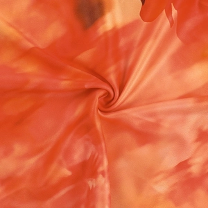 Detail of soft silk-like fabric featuring an orange-red abstract floral print and texture
