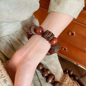 Detail of vintage round wood beads and coconut shell bracelets on a woven straw bag