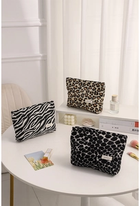 Three assorted leopard and zebra print makeup bags arranged on a white table