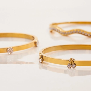 Dettaglio del bracciale dorato in acciaio inossidabile con ciliegia in strass e onde