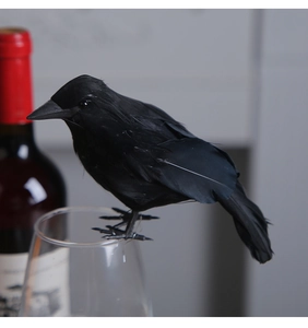 Realistic black feather crow perched on wine glass for Halloween party table decoration