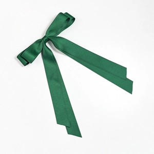 Close-up of dark green satin double-layered bow hair clip with long ribbons and silky texture