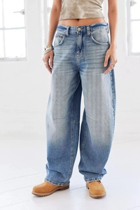 Detailed texture of light blue washed denim fabric and distressed edges on wide leg jeans
