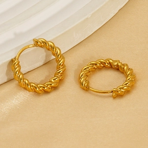 Elegant gold-plated twisted hoop earrings displayed on a premium stone and satin surface