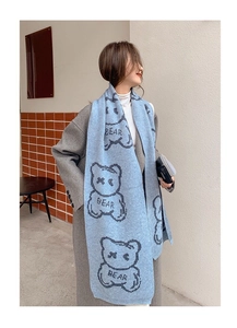 Detailed view of blue knitted scarf featuring grey bear patterns and woven BEAR text