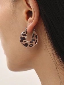 Close-up of C-shaped resin earrings with leopard print worn by model for detail