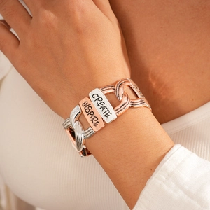Detail of silver and rose gold link bracelet with Inspire and Create engraved tags