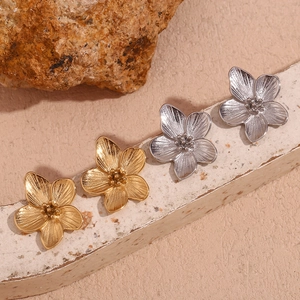 Macro detail of 18K gold and silver plated stainless steel floral stud earrings