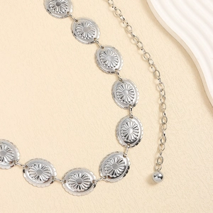 Detail of vintage silver waist chain featuring engraved radial flower patterns and metal links