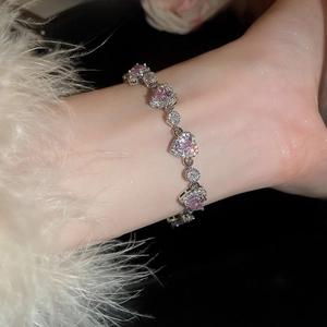 Detail of zircon heart bracelet with pink gemstones and round diamonds on model's wrist