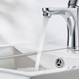 Close-up of stainless steel straw being cleaned with a nylon brush under a water faucet
