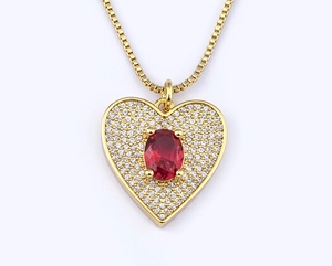 Detailed view of a gold heart pendant featuring a red oval gemstone and pavé diamonds