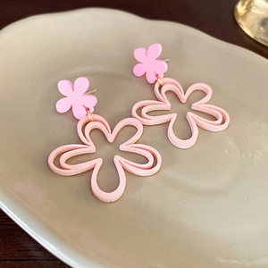 Detailed view of pink resin flower earrings on a ceramic dish with gold metal accents