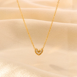 Elegant gold heart necklace with sparkling zircon pavé on pleated silk background