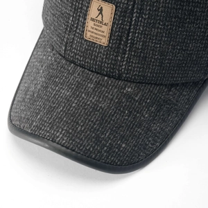 Detail of grey wool baseball cap showing textured fabric and embossed leather logo patch